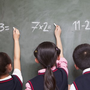 Three children doing math equations on blackboard - Calculate